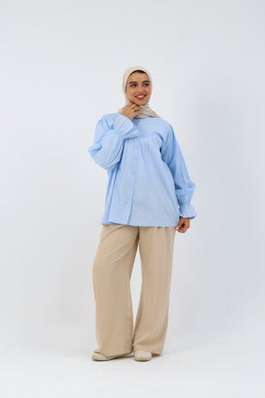 Baby blue THT GIRL Lady Blouse displayed on a hanger, showcasing its soft fabric and stylish design.