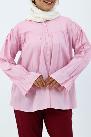 Baby pink THT GIRL Lady Blouse with long sleeves and ruffle details, displayed on a hanger against a neutral background.