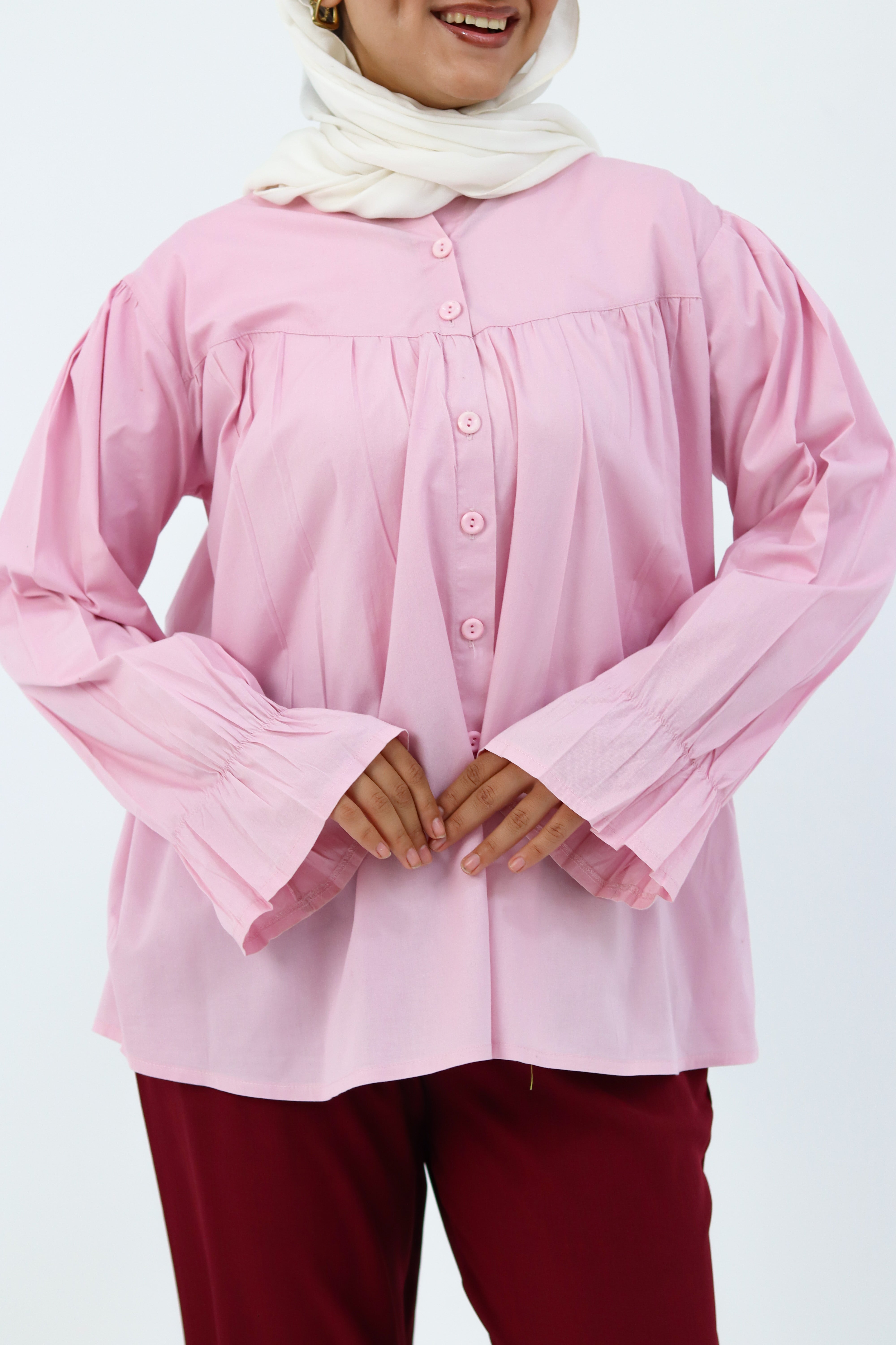 Baby pink THT GIRL Lady Blouse with long sleeves and ruffle details, displayed on a hanger against a neutral background.