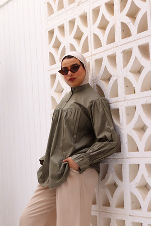 Olive THT GIRL Lady Blouse displayed on a hanger, featuring a stylish, lightweight design with a V-neck and long sleeves.